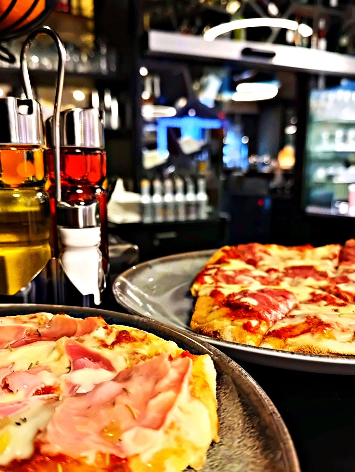Pinsa Cardinale mit Schinken und Pinsa Salami auf grauen Tellern